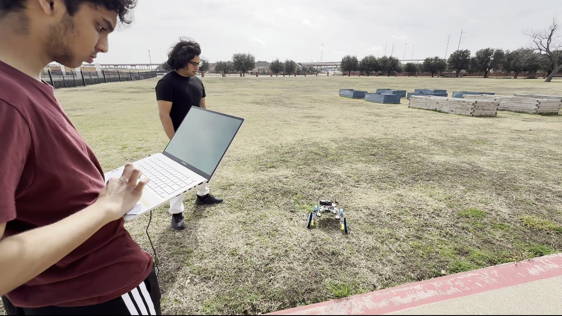 Team controlling rover with laptop outdoors